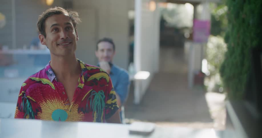 Young man with a colorful shirt ordering food from a food truck in the morning