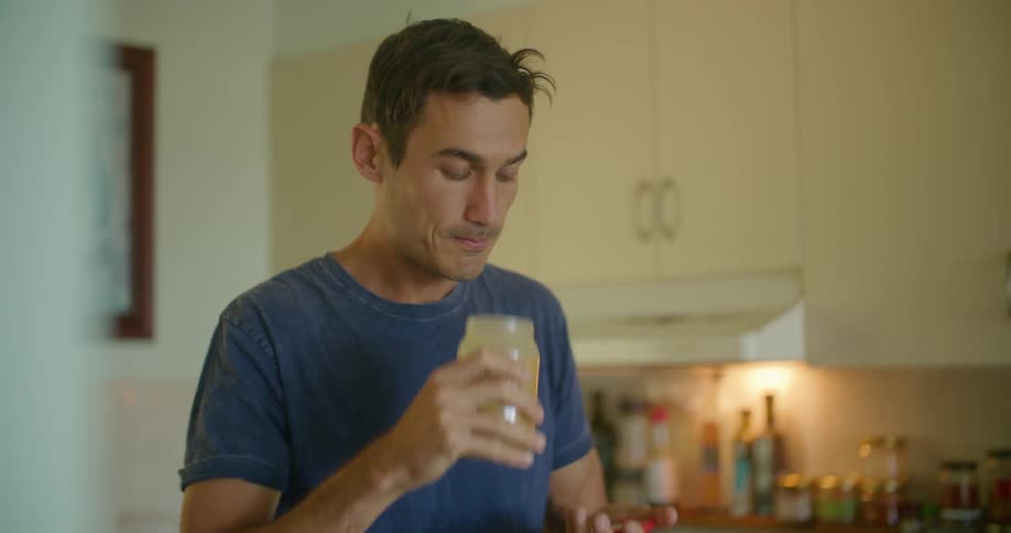 Man drinks mixture while cooking in kitchen