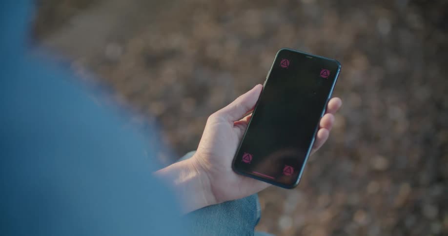 A person holding a phone with a replaceable screen outdoors