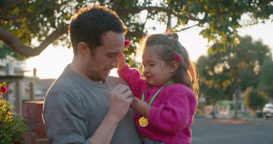 A girl hands a flower to a man who puts it behind his ear