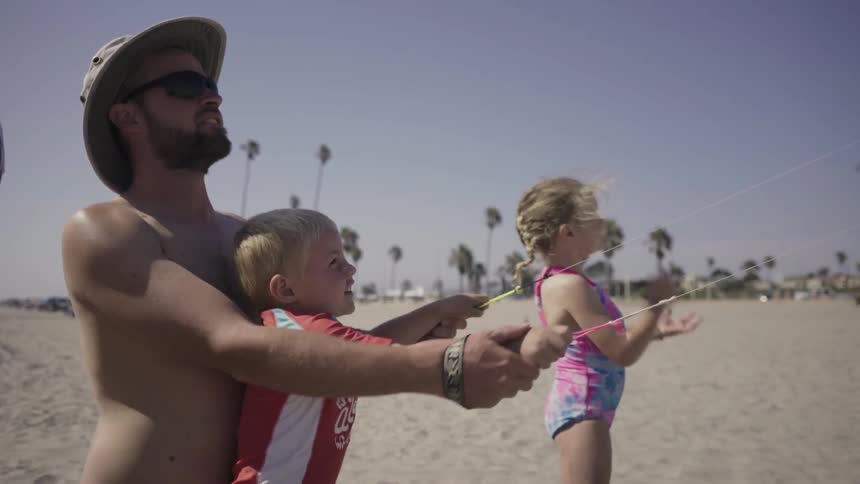 Man helping a child steer a kite on the beach
