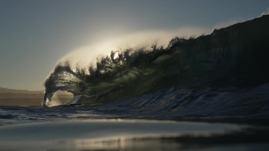 A large wave crashes onto the beach
