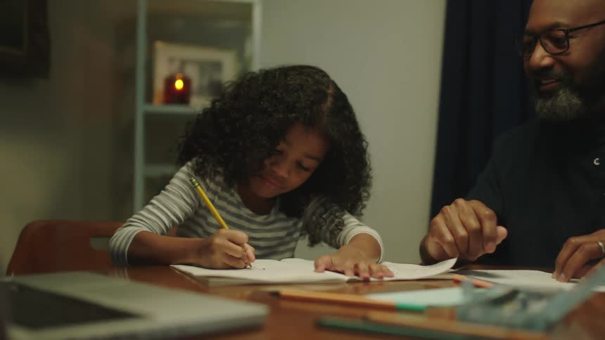 Father helping daughter with homework on the dinning table at home