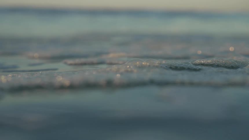 Foamy bubbles sit on the top of a clear blue ocean
