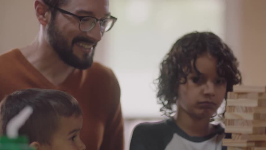 Father and children play wood stacking tower game