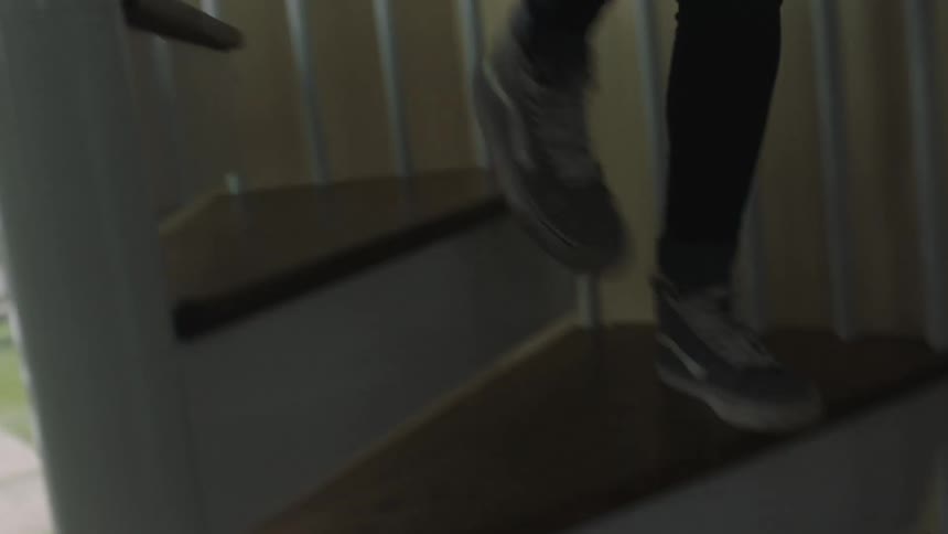 A woman climbs down the stairs at home
