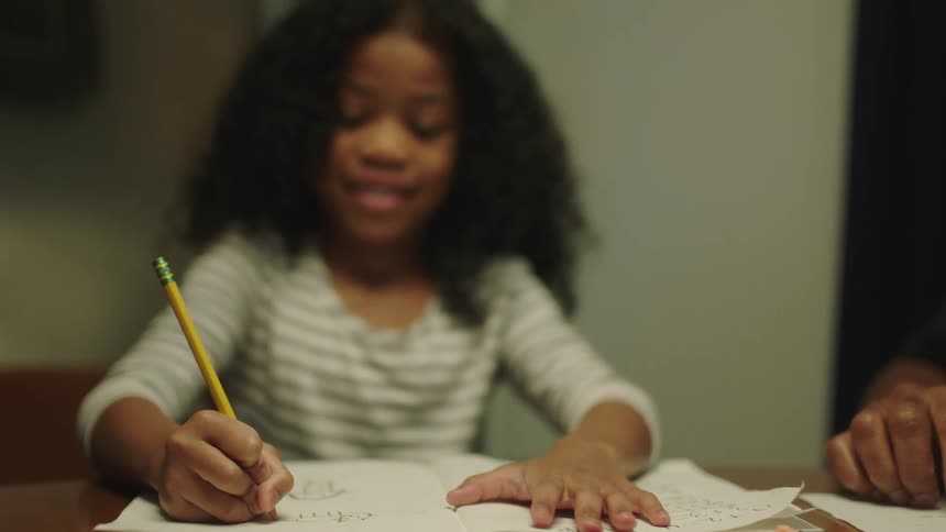 A girl is doing her homework with a pencil