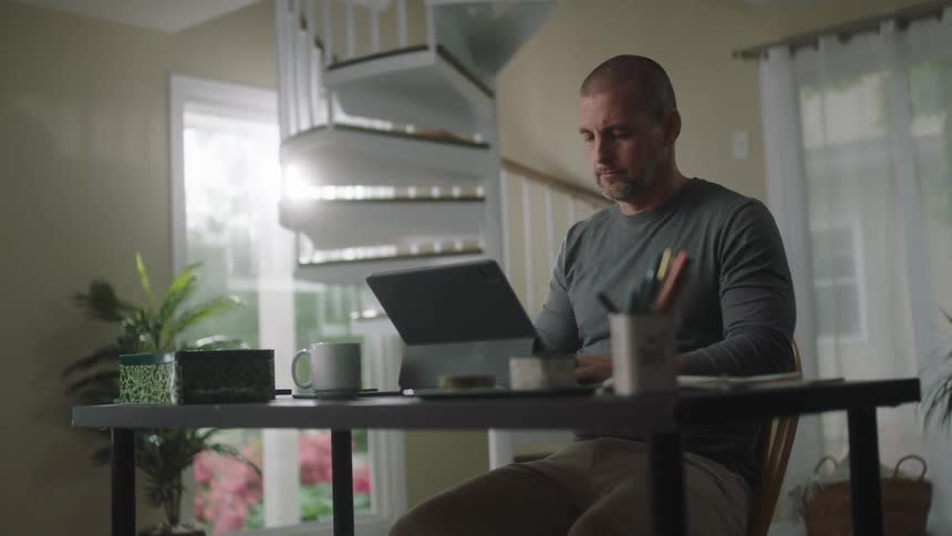 Man sitting at a desk at home working on a laptop in the morning