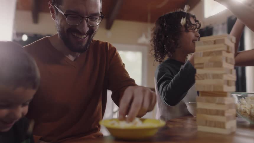 A family has fun throwing popcorn and playing a board game