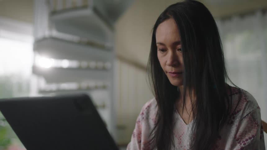 A woman is typing on her laptop
