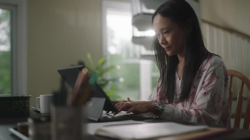 A woman sits at the desk typing