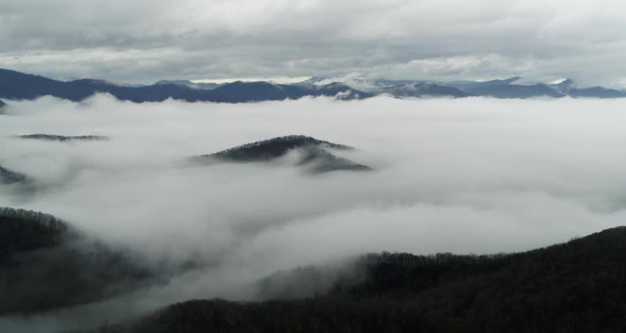 Heavy fog fills valley under overcast sky