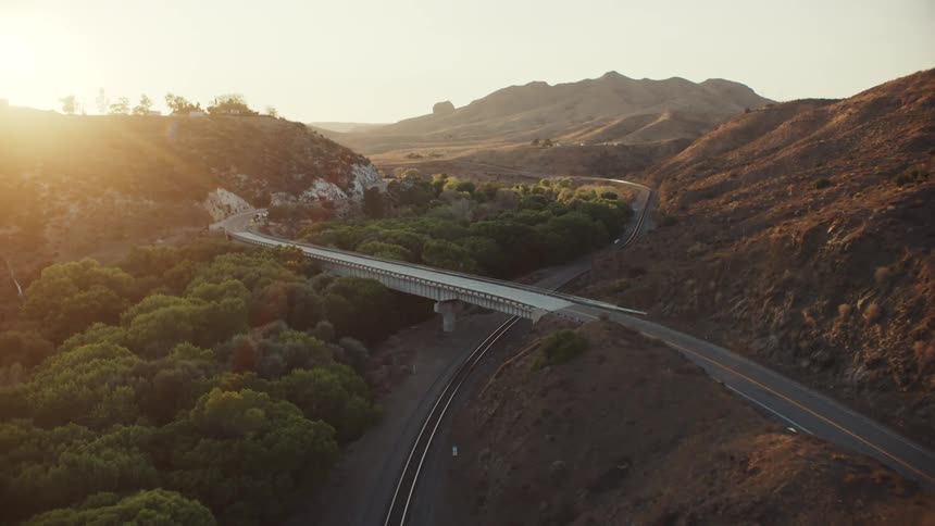 Aerial view of bridge crossing railroad track and green valley