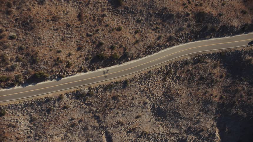 Top down aerial view of a white van driving on a road in the countryside
