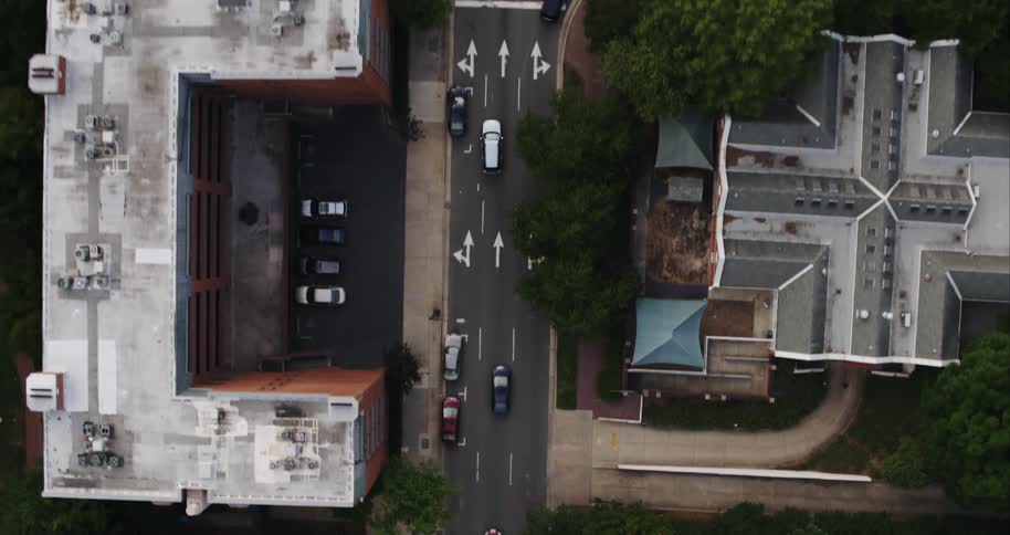 Cars drive along road past building toward intersection