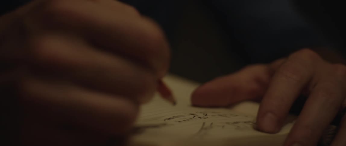 A person scribbles in a notebook