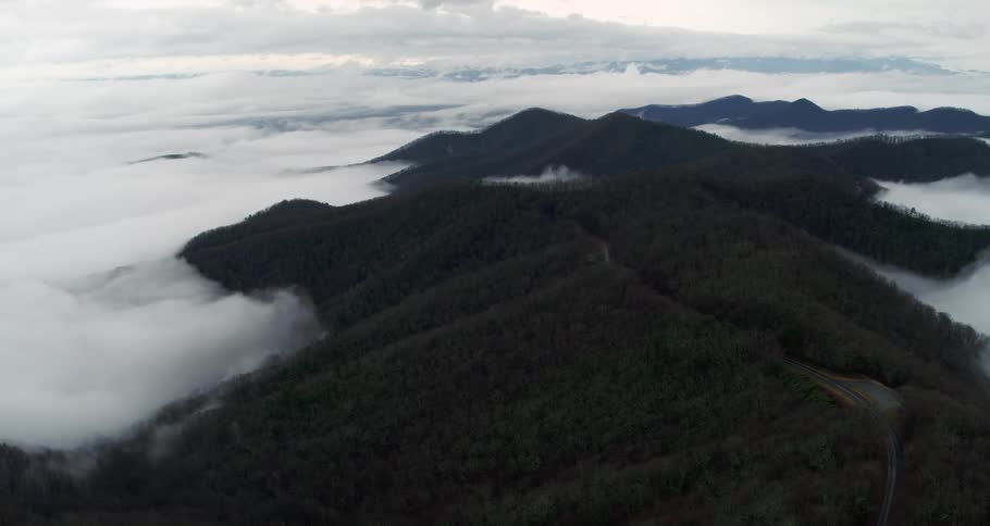 Clouds move over mountains covered with trees high in a cloudy sky