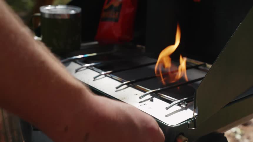 A man lights a flame on a grill outside