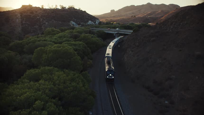A train travels on the tracks through the mountain range