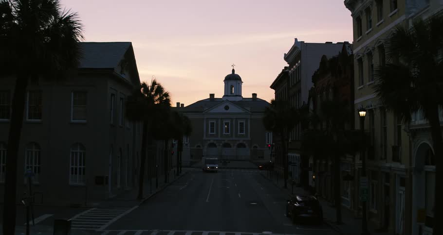 Vehicles travel down the city street at sunset
