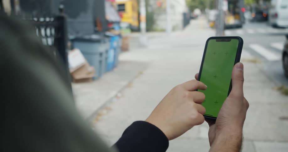A man and woman type on a smartphone while standing on a city block