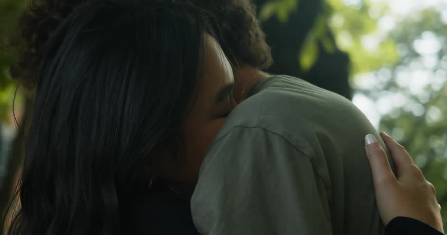 Couple hugs standing near tree across from apartment building