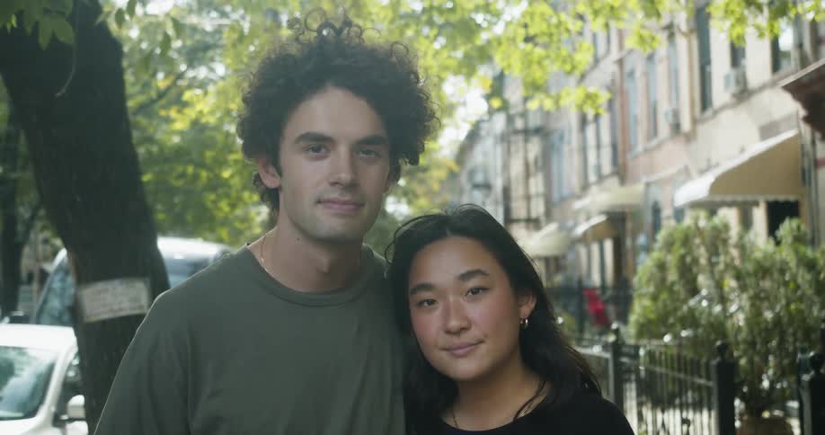 A couple pose together by an apartment building