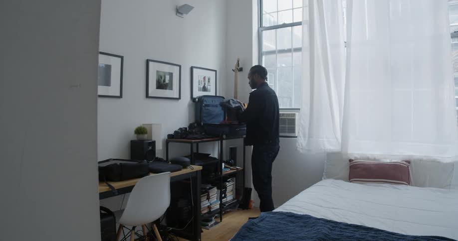 A man packing a suitcase in his room
