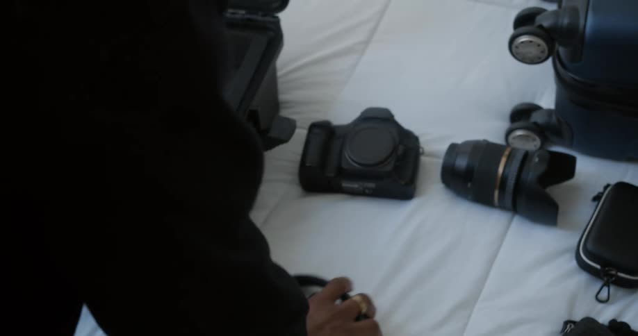 Man packing photography equipment on a case over the bed inside a room