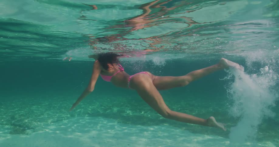 Woman wearing pink bikini swims keeping her head above water