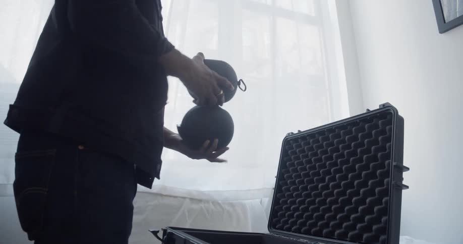 Photographer packing equipment in a case over a bed in the bedroom