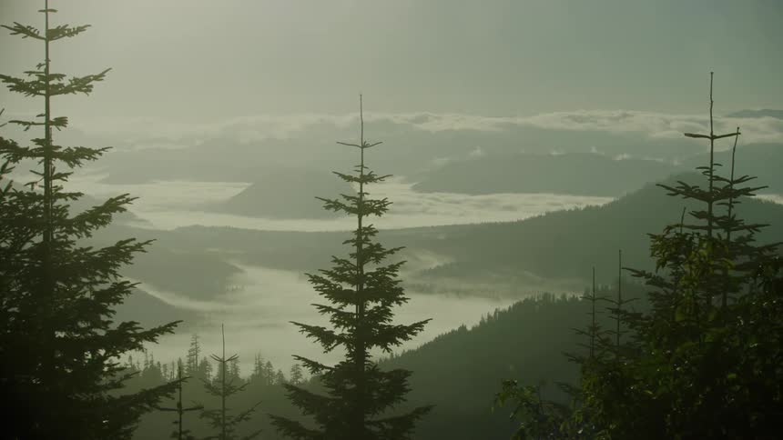 Fog hangs heavy in the valley below as the camera slowly moves revealing the majestic scene from high above