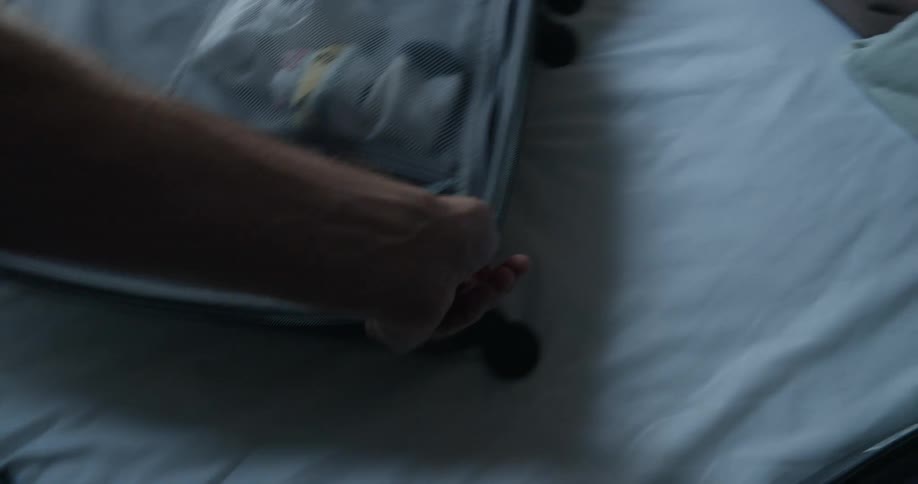 Person zips inner compartment of open suitcase