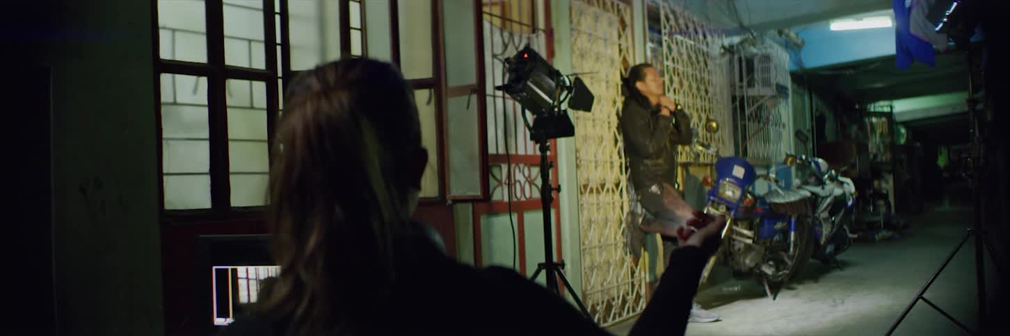 Camera crew move lighting and camera around as one woman watches screen