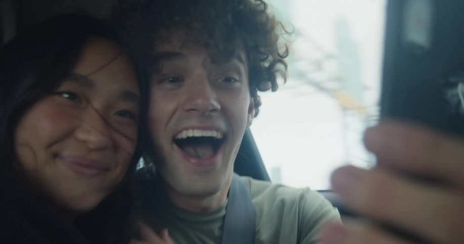 Two passengers in a car are taking a selfie while traveling in highway traffic during the day