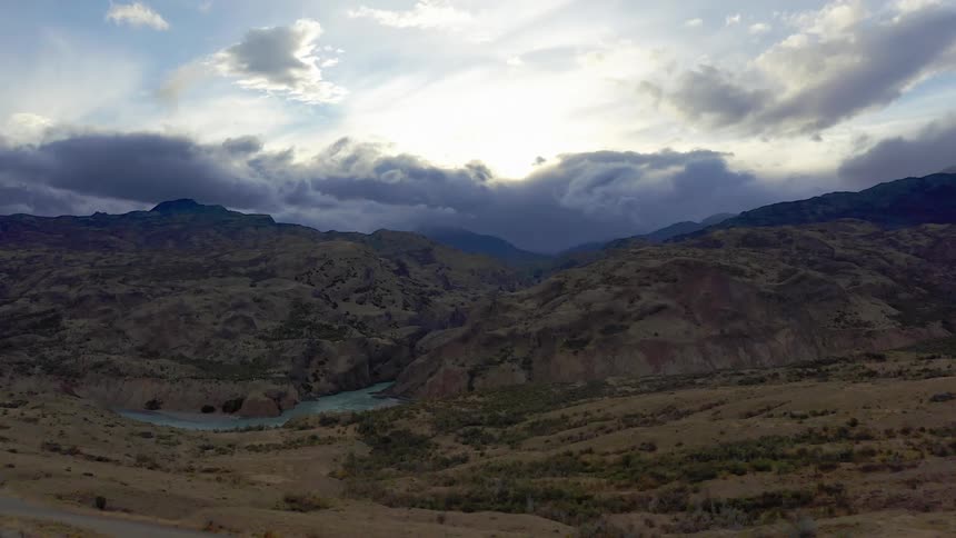 Aerial shot of a large river gorge and swirling mountain clouds in Patagonia