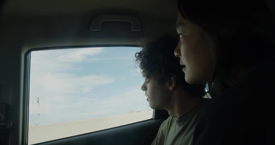 Young couple talking and pointing out the window on the backseat of a car driving on the city