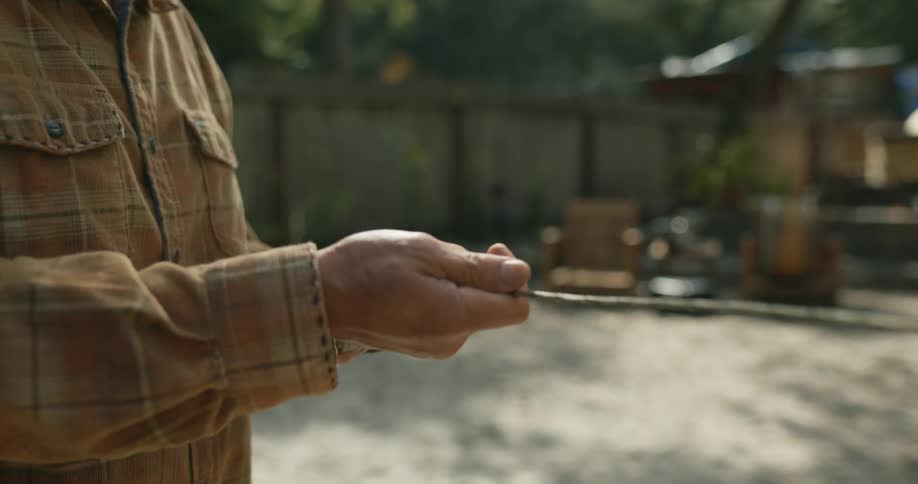 A man rolls out a cable in his yard
