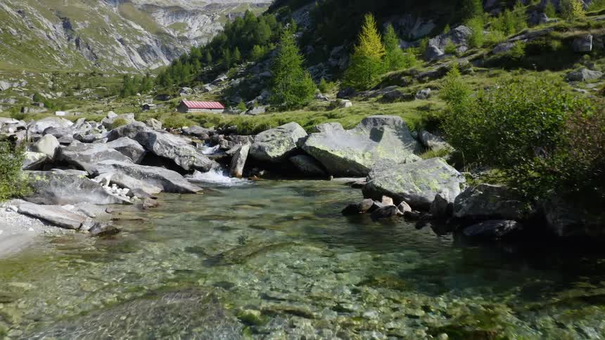 Building sits in valley between stream and forest covered mountain