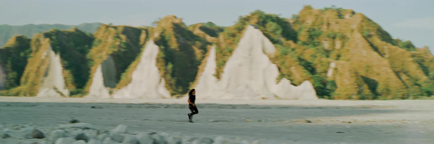 Man runs across sandy valley between mountains on misty day
