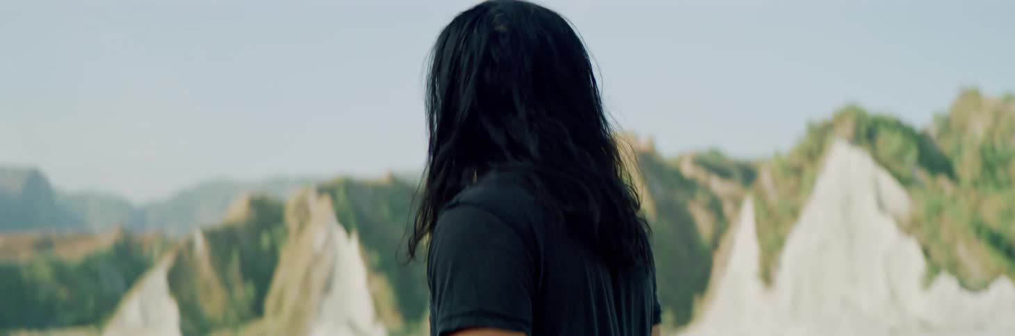 A man stands up looking around at the mountains