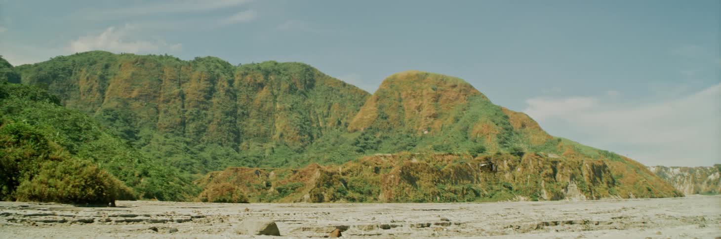Helicopter flying close to the ground near the green slopes of a mountain range