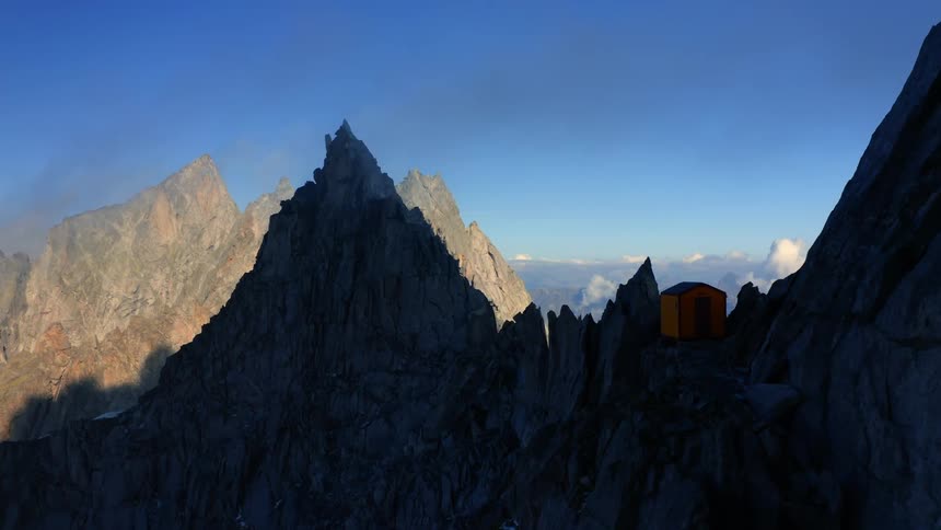 Aerial view of the jagged peaks of a mountain range in the morning shadow