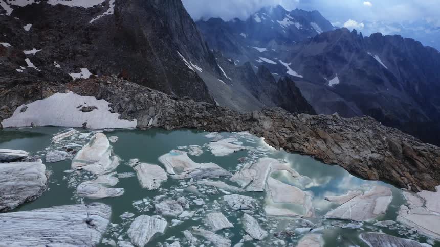 Aerial view of a frozen lake on the peak of a mountain range under the clouds