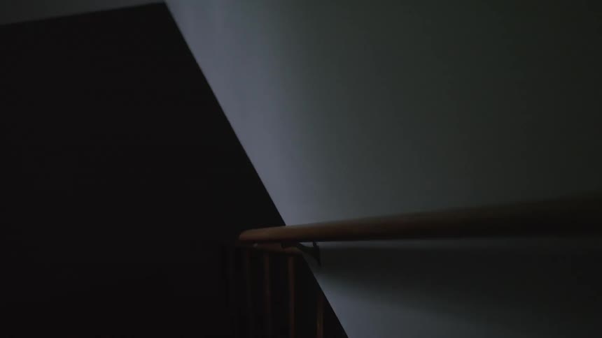 A hand rail on an interior wall in dim light