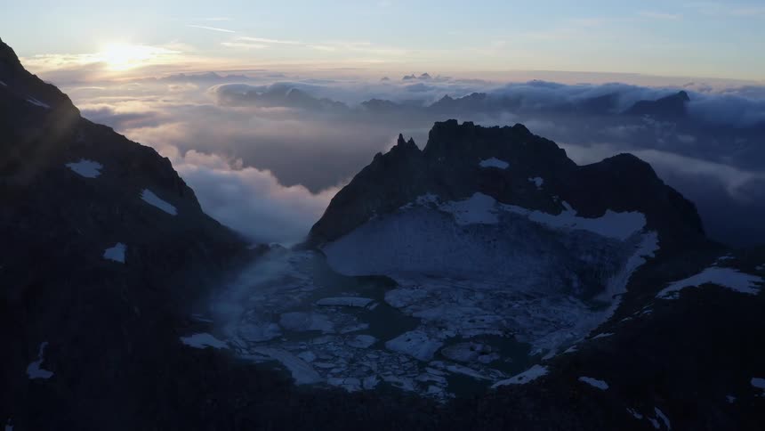 Ice floats on water in crater topping mountain on sunny day