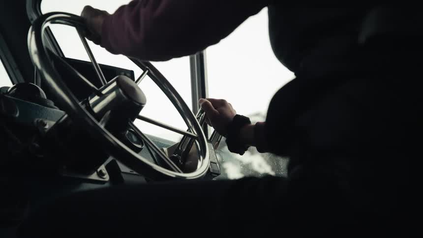 A person is steering the large wheel in the ship