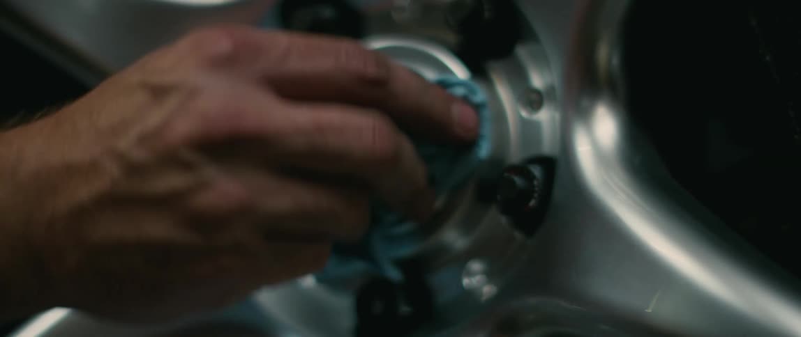 A man wipes the chrome rims of his vehicle with a towel