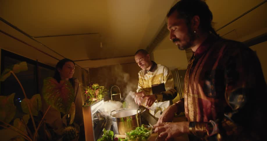 A group of people standing around in a kitchen