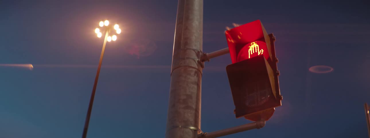 A traffic light glows red with a hand signal for stop